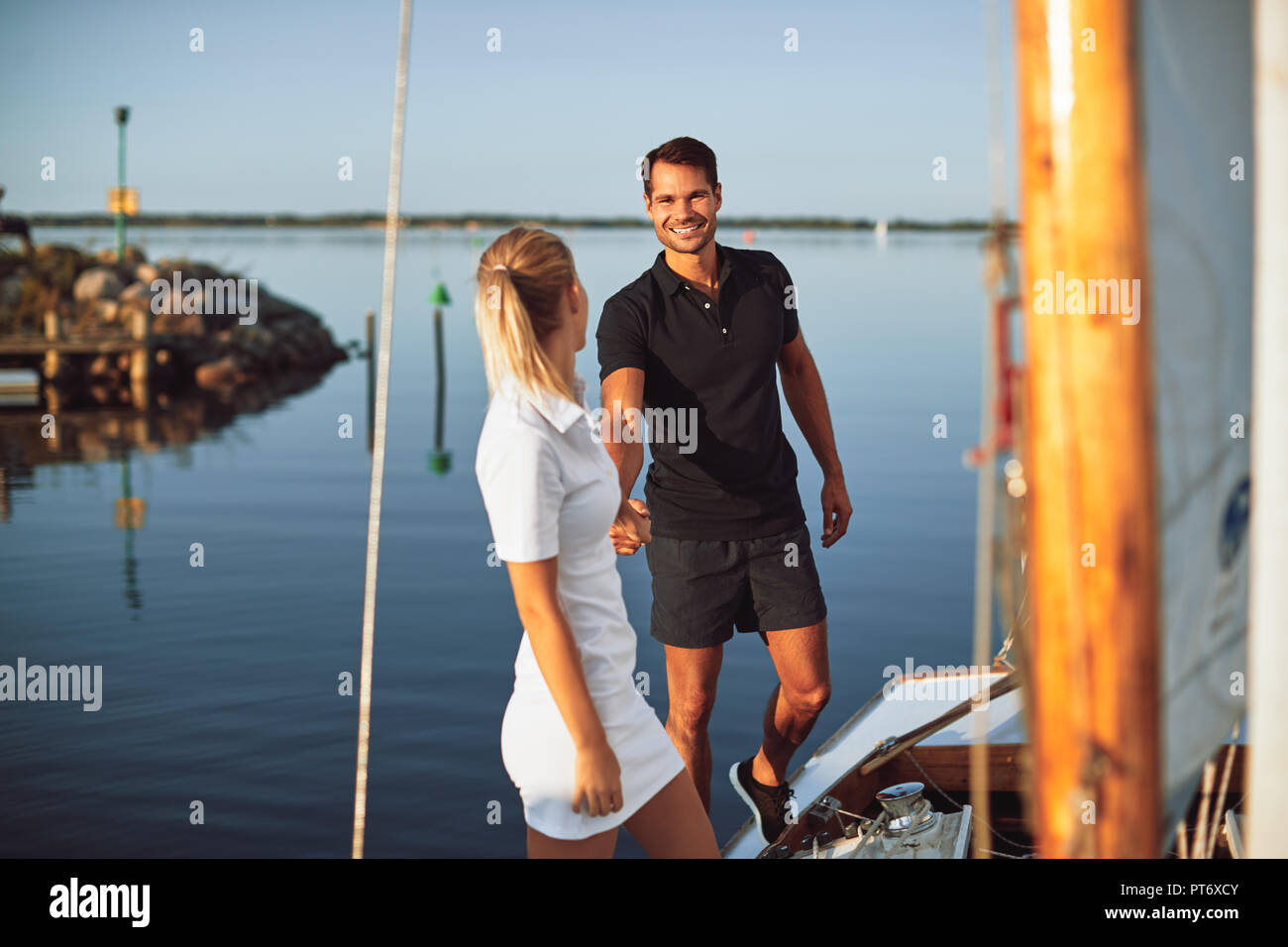 Young woman leading her husband by the hand along the deck of a yacht while enjoying a sunny day sailing together Stock Photo