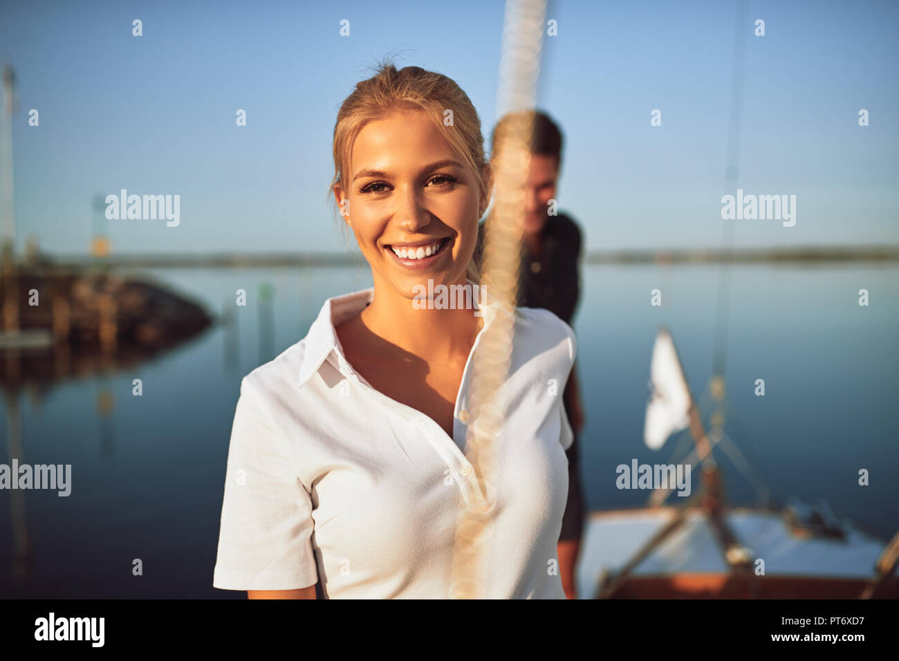 Smiling young woman standing with her husband on the deck of a yacht while enjoying the day sailing together Stock Photo
