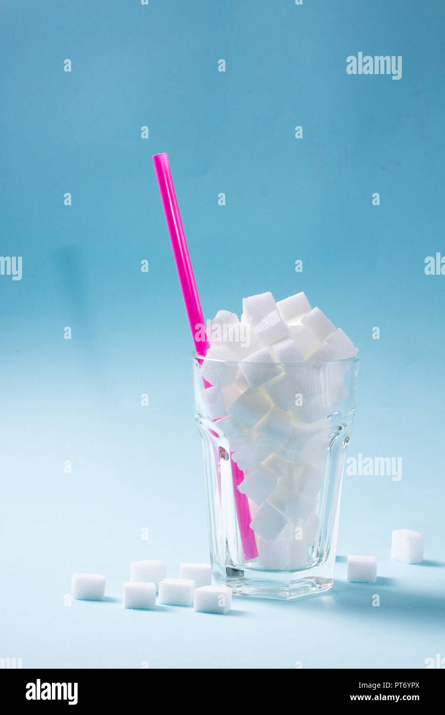 Sugar cubes in glass, diabetes and sugar overuse concept, blue