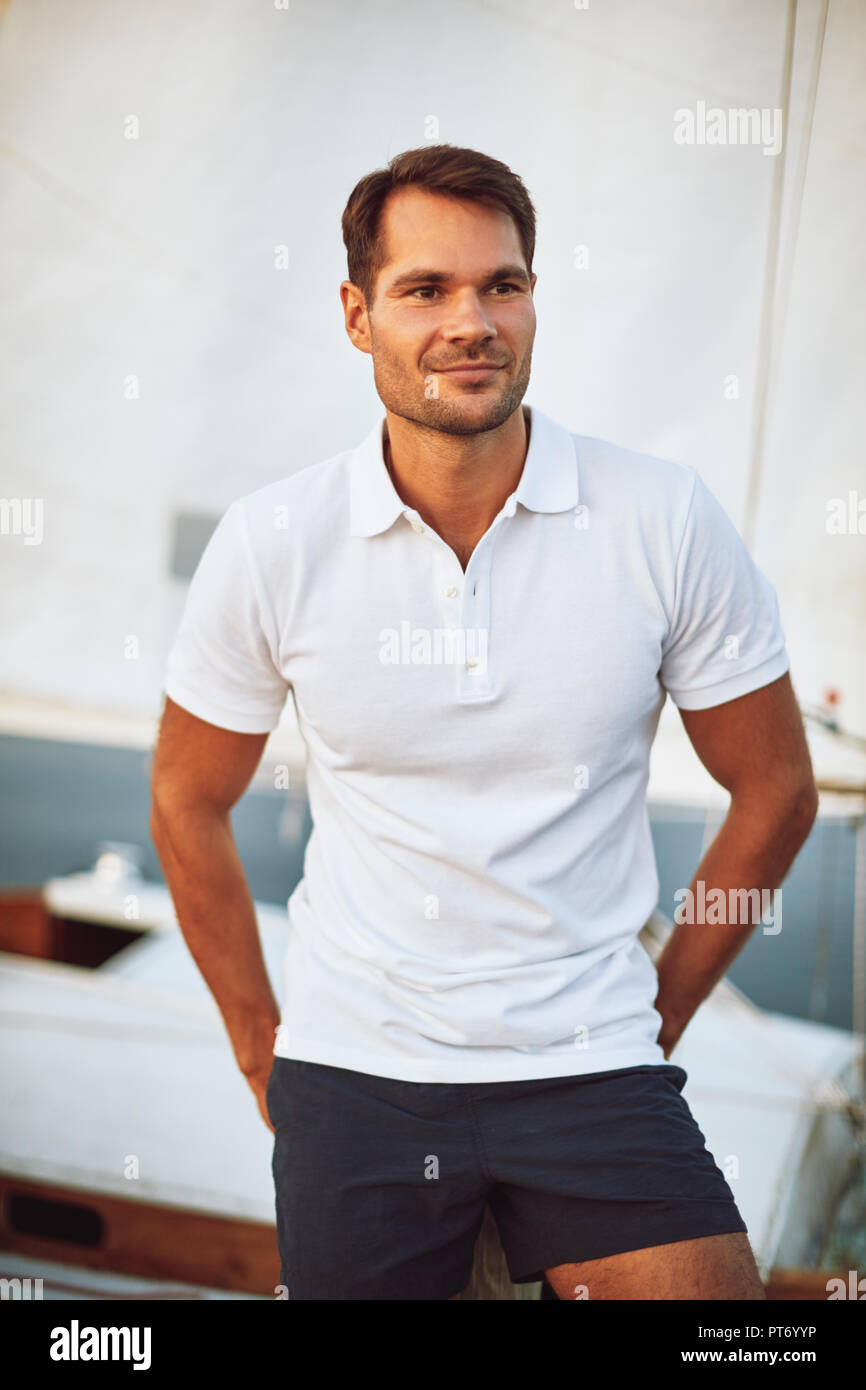Handsome young man standing alone on the deck of his yacht enjoying a sunny day sailing Stock Photo