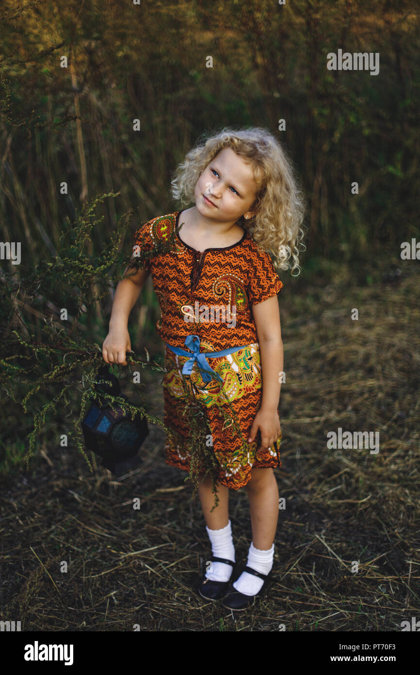 little curly blonde girl holding a vintage lantern Stock Photo