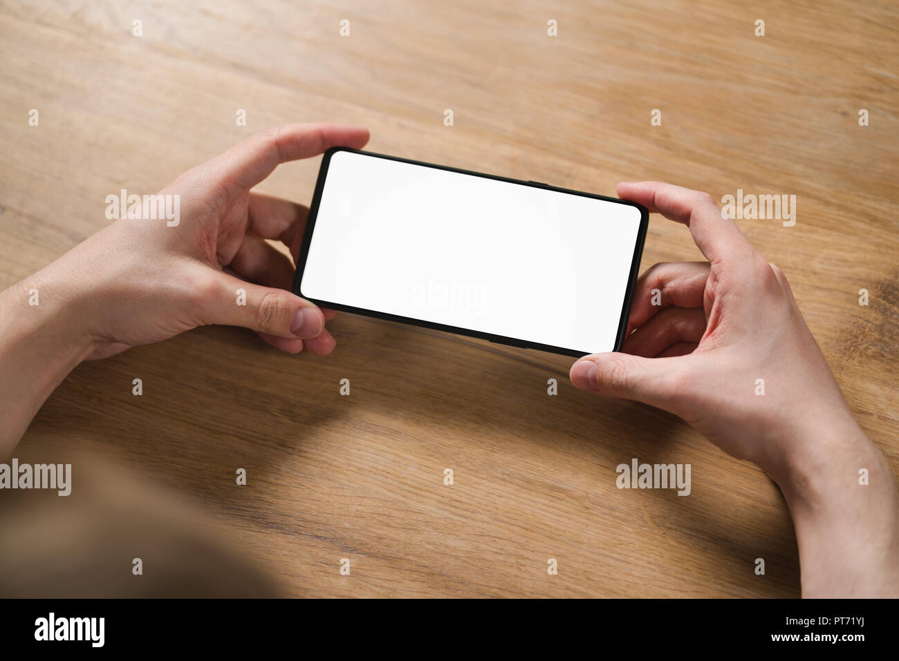 young man hands holding smartphone with blank white screen in landscape mode, template Stock Photo