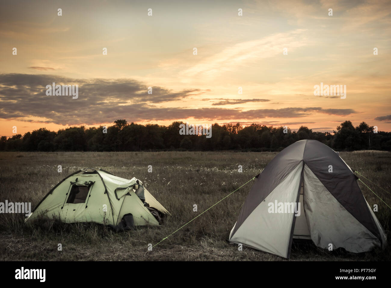 Camping tents on camping sites on summer flatland field plain and dramatic sunset sky during camping holidays Stock Photo