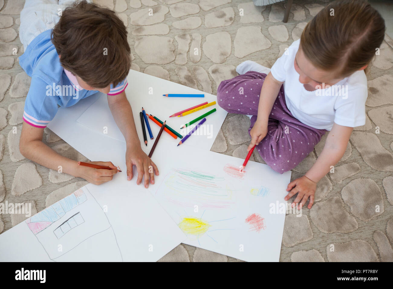 Little boy and girl drawing with color pencils on the floor playing ...