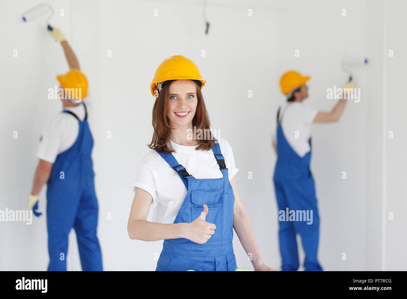 Two young workers in uniform painting the wall Stock Photo