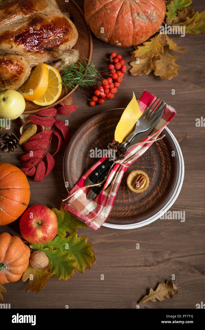 Thanksgiving dinner background with turkey, fall leaves and seasonal autumnal fruits decor around plate, top view. Autumnal festive table setting. Stock Photo