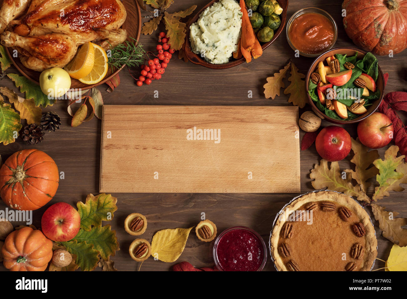 Autumn festive Thanksgiving dinner background with Turkey and traditional sides dishes around Wooden Board, copy space for text, menu design, seasonal Stock Photo