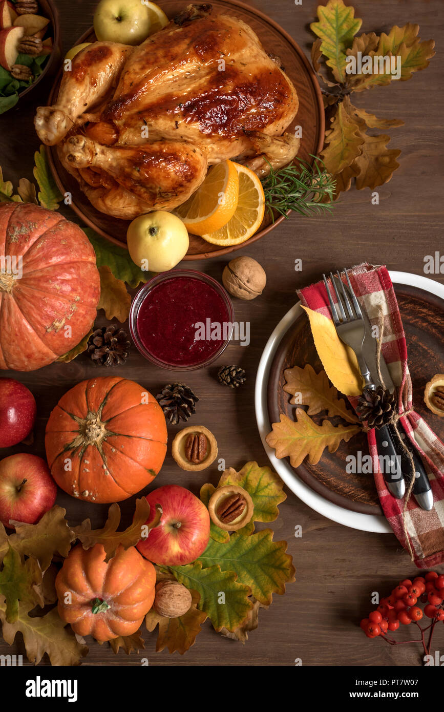 Thanksgiving Dinner background with Turkey, fall leaves, seasonal autumnal fruits, decor and table setting, top view. Stock Photo