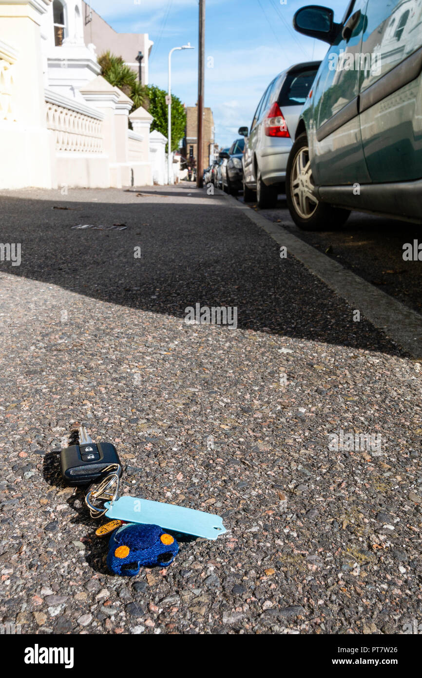 Dropped car keys on pavement in street. Wide angle view of keys next to