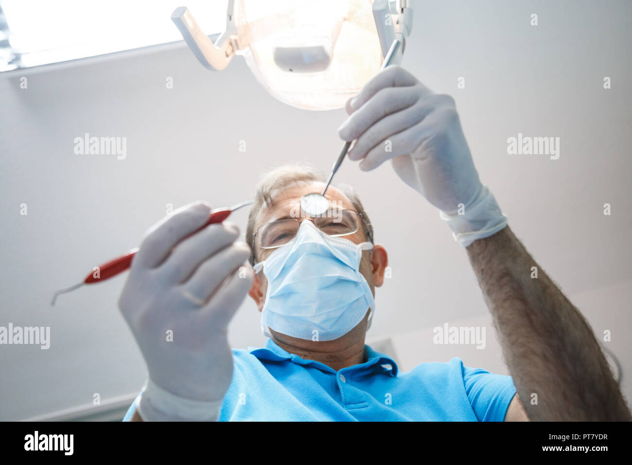 From below shot of man in uniform and gloves using tools and doing oral ...