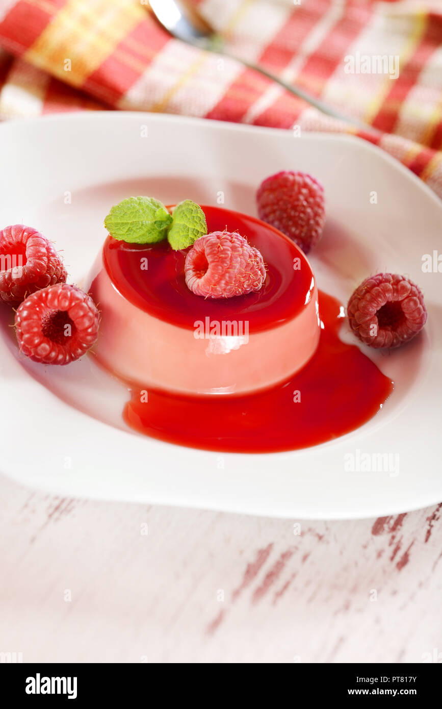 Panna cotta dessert with frsh raspberries and mint leaves on top Stock Photo
