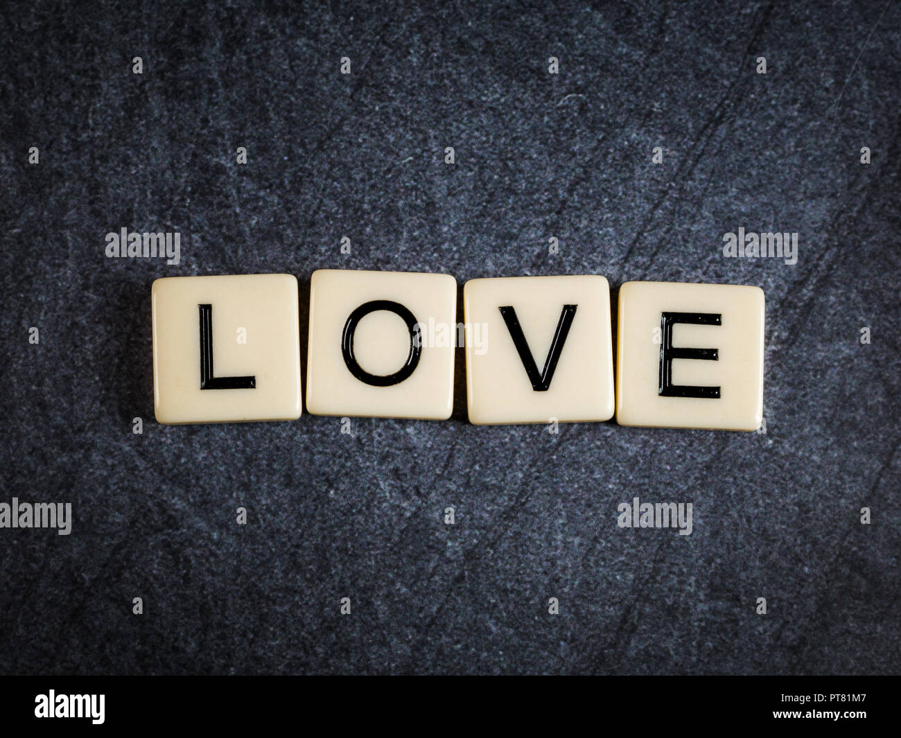 Letter tiles on black slate background spelling Love Stock Photo