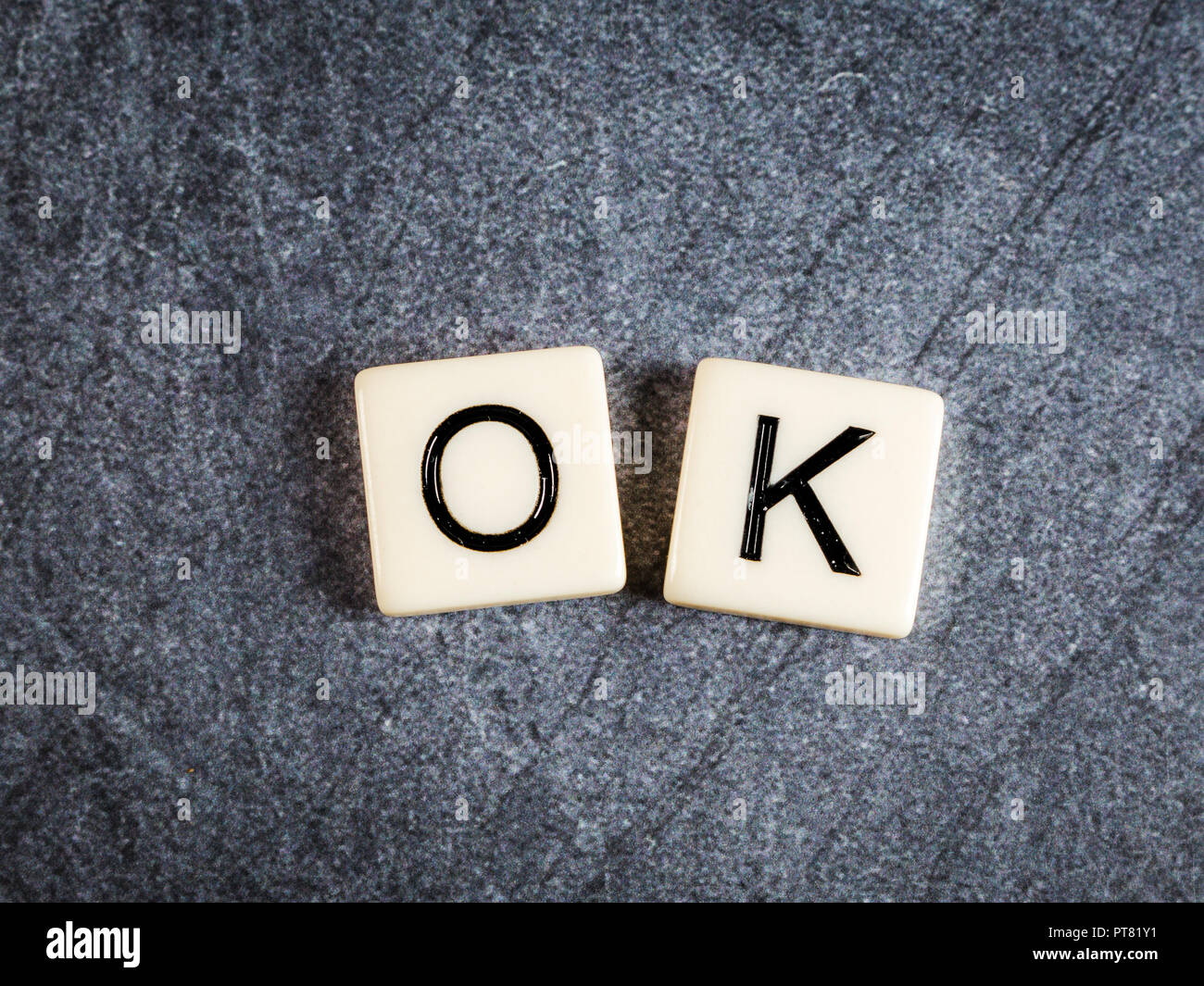 Letter tiles on black slate background spelling OK Stock Photo Alamy