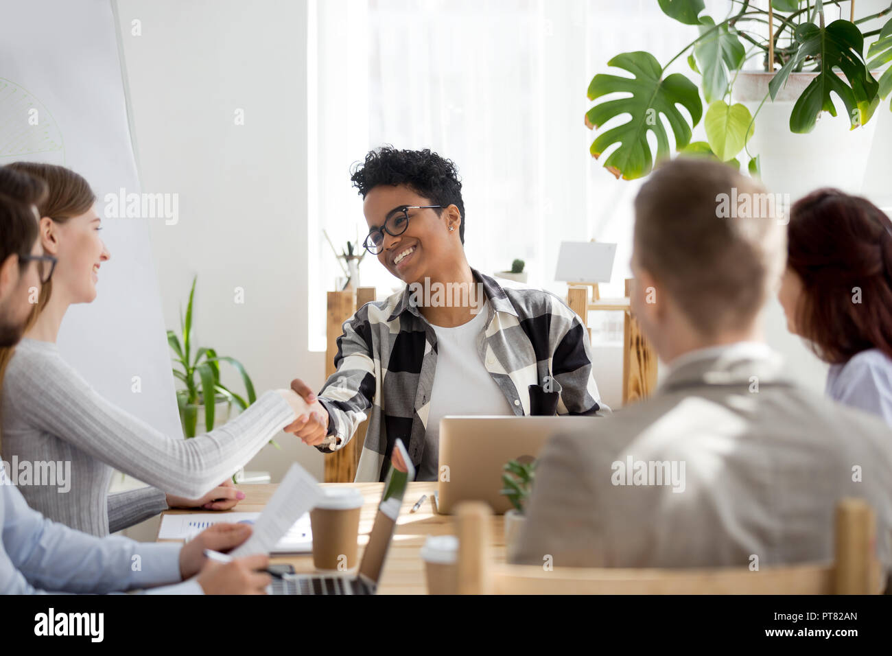 Happy businesspeople handshaking in office at meeting Stock Photo