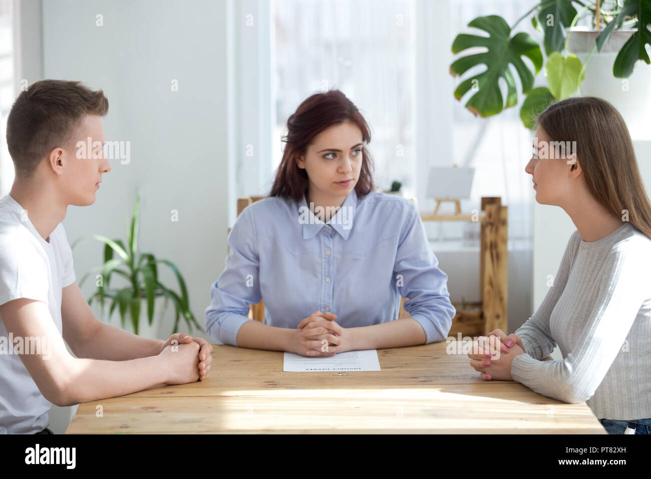 Three young people sitting at the desk in office Stock Photo