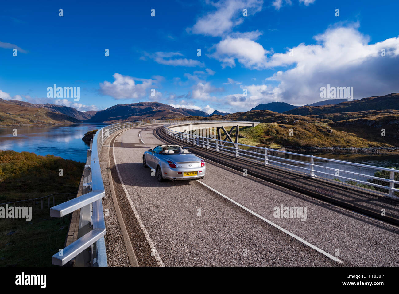 A convertible sports car driving over the Kylesku Bridge, North coast 500 Sutherland, Highland, Scotland, UK Stock Photo