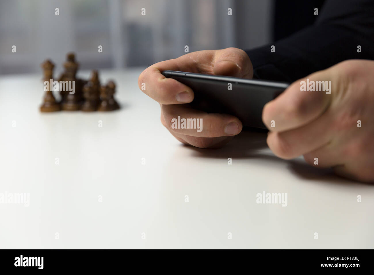 Businessman with phone planning strategy with chess figures on table. Strategy, leadership and teamwork concept. Stock Photo
