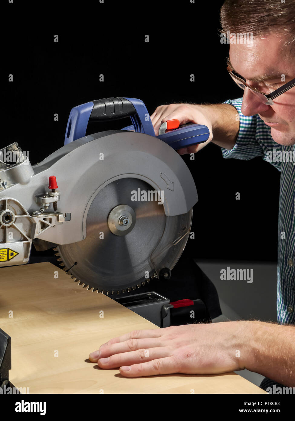 Carpenter cutting flaxboard using sliding compound mitre saw Stock Photo