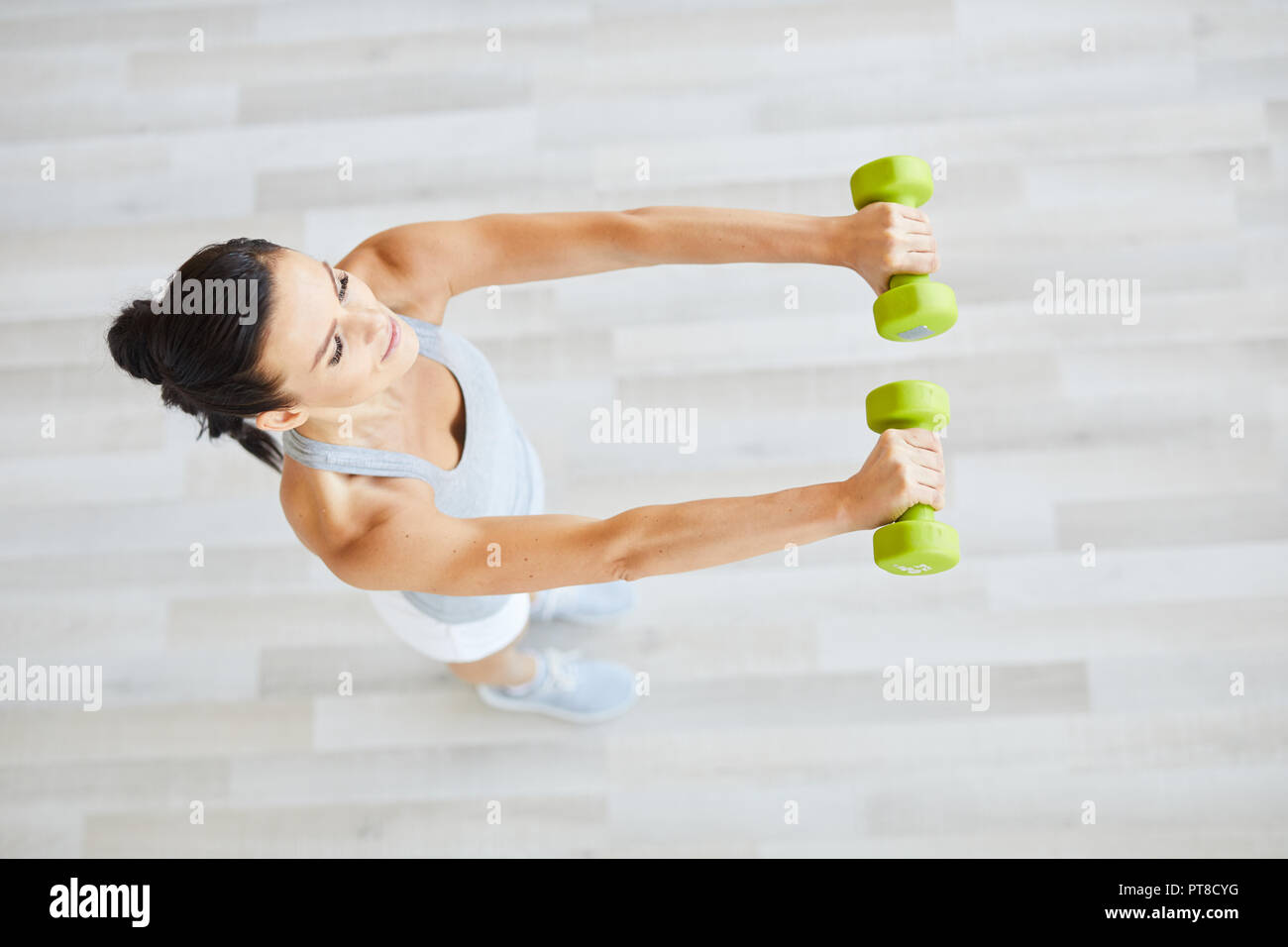 Overview of young female stretching her arms forward while doing exercise with dumbbells Stock Photo Alamy
