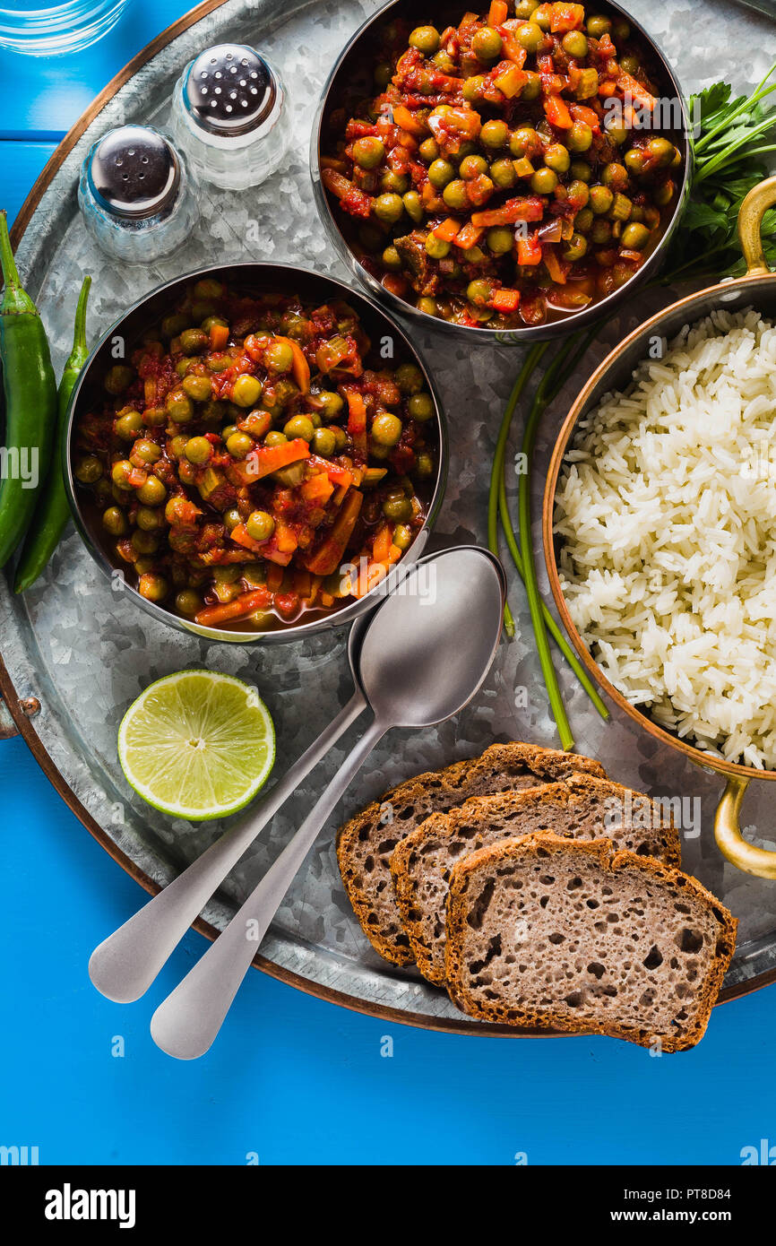 vegan curry with green peas and basmati rice served on a blue table