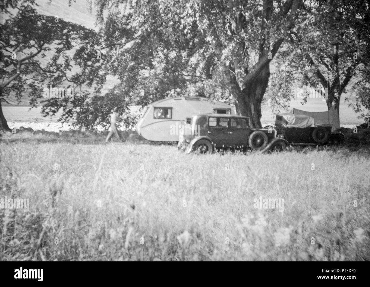 Photograph taken in England during the early 1930s showing a car and caravan in a field. Stock Photo