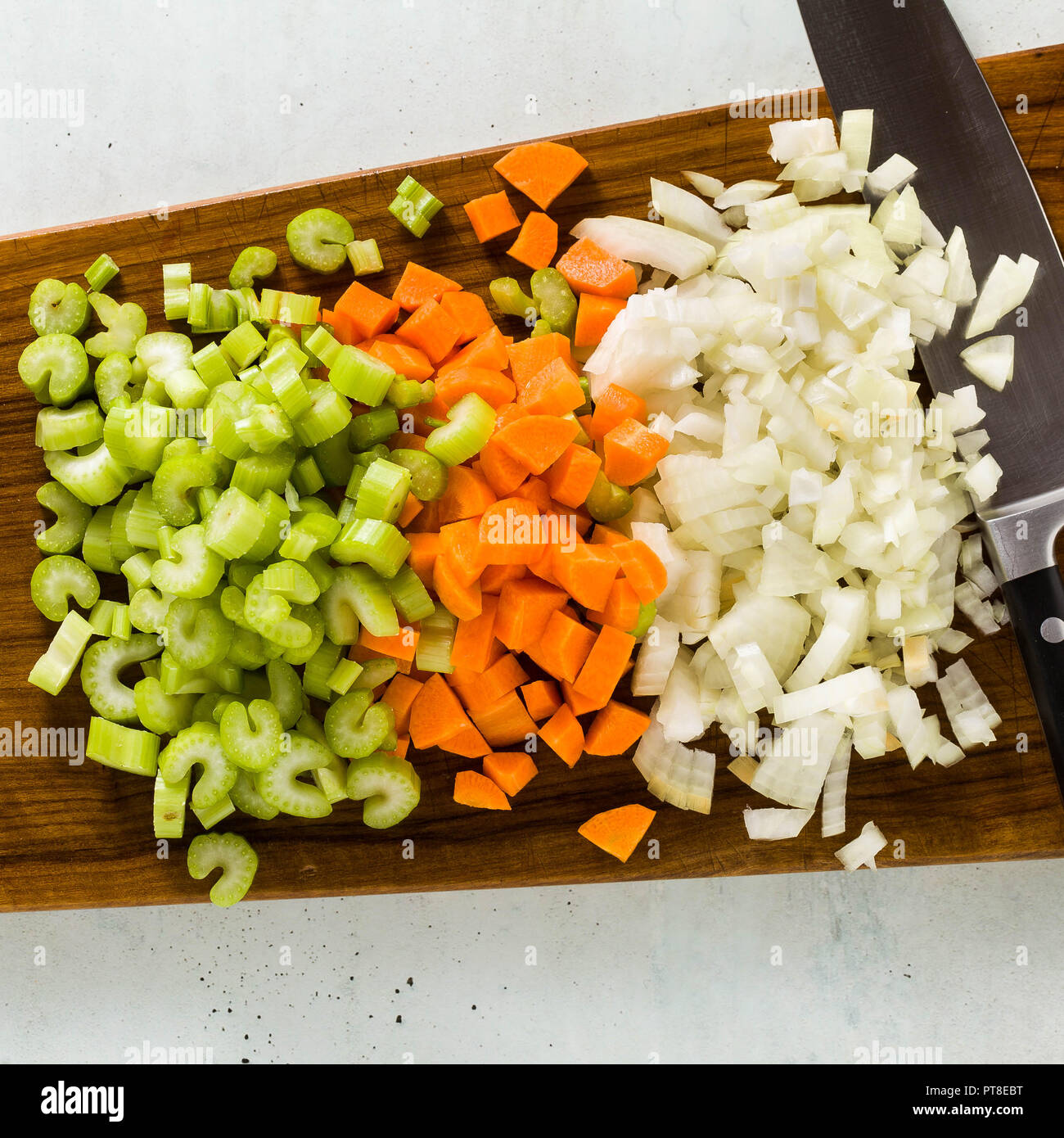 chopped vegetables and a chef's knife on a wooden cutting board. Basic cutting for restaurants or home cooking. Stock Photo
