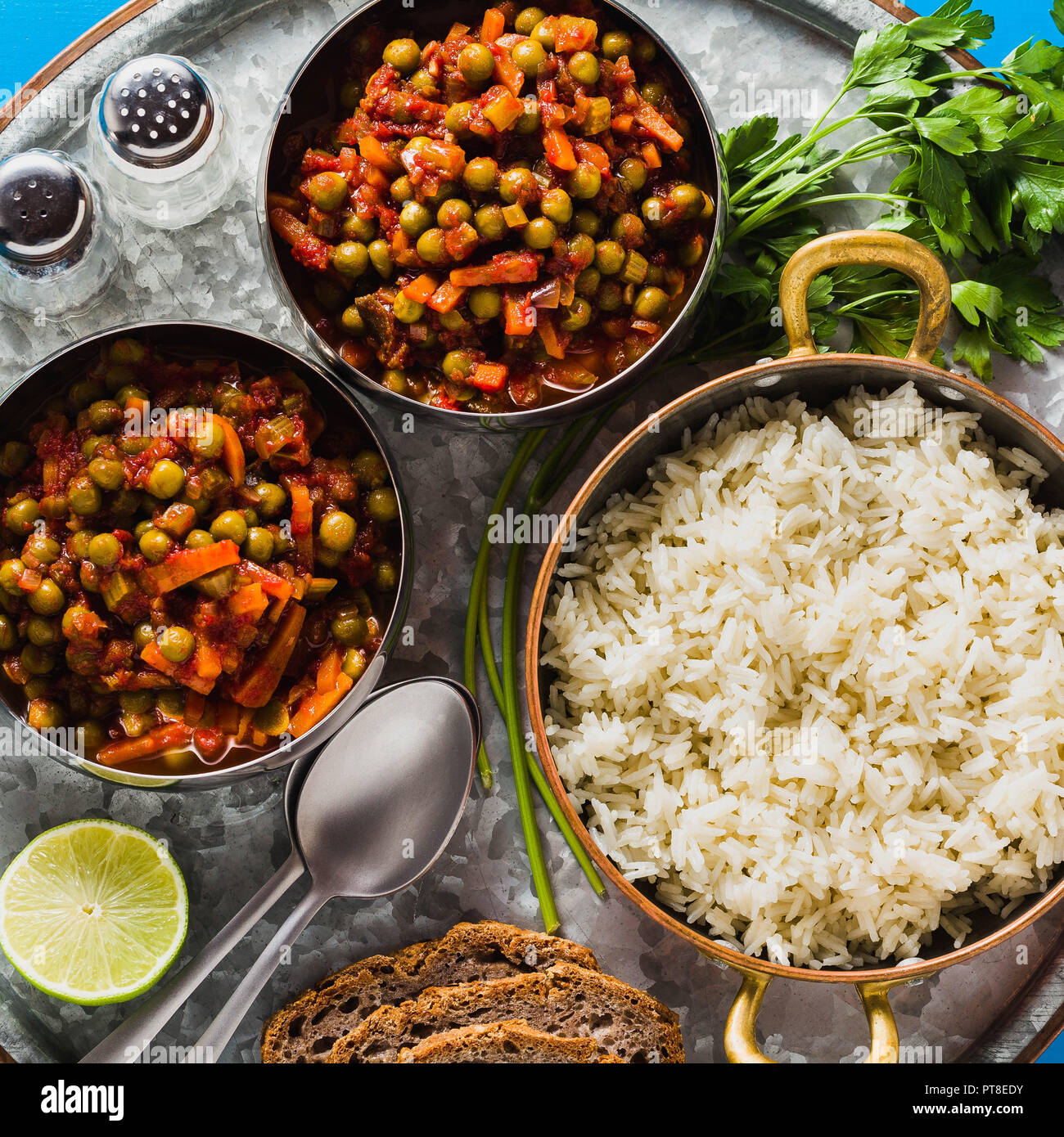 vegan curry with green peas and basmati rice served on a blue table