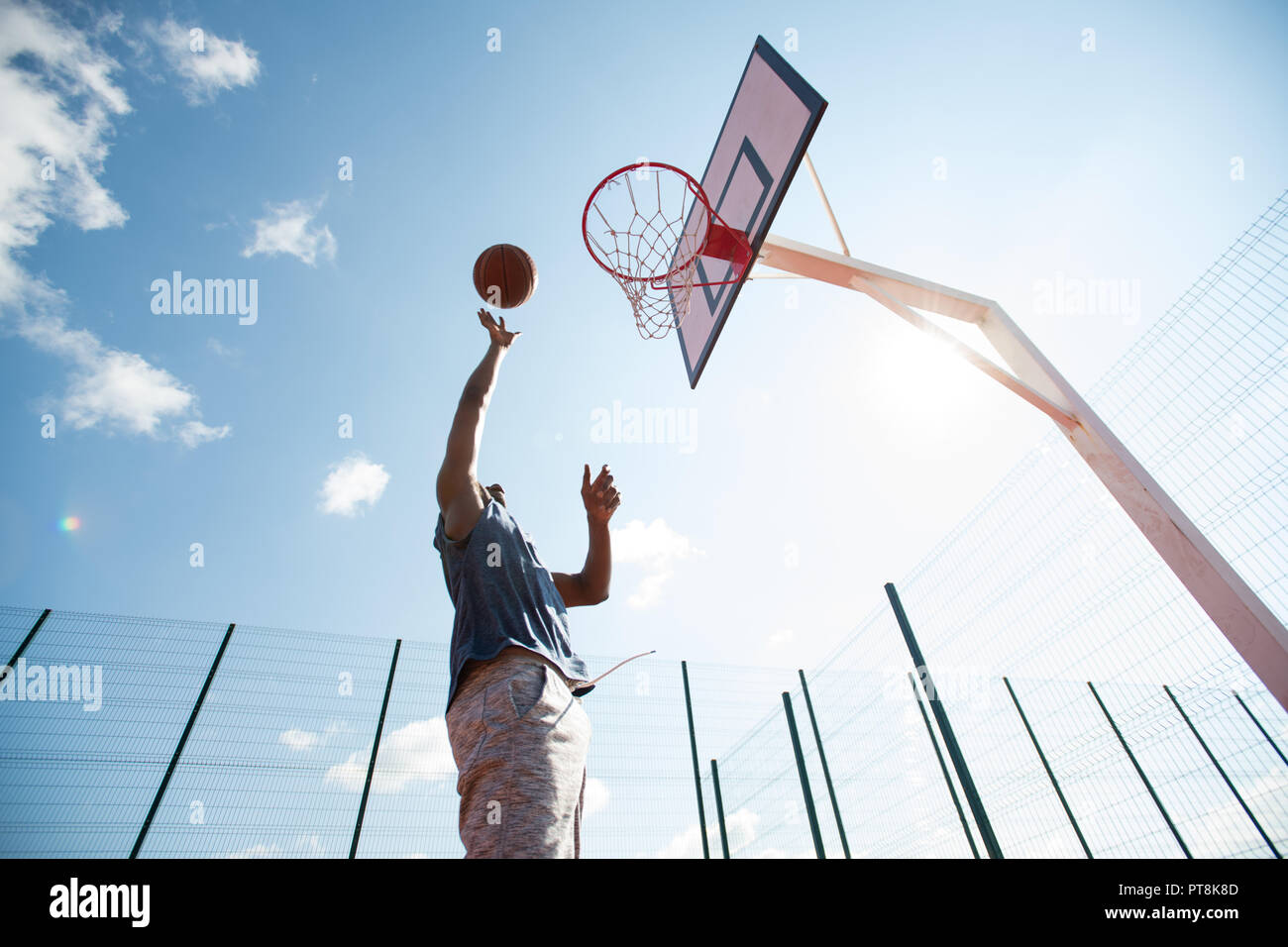 Low Angle Action Shot Of African Man Jumping In Basketball Court