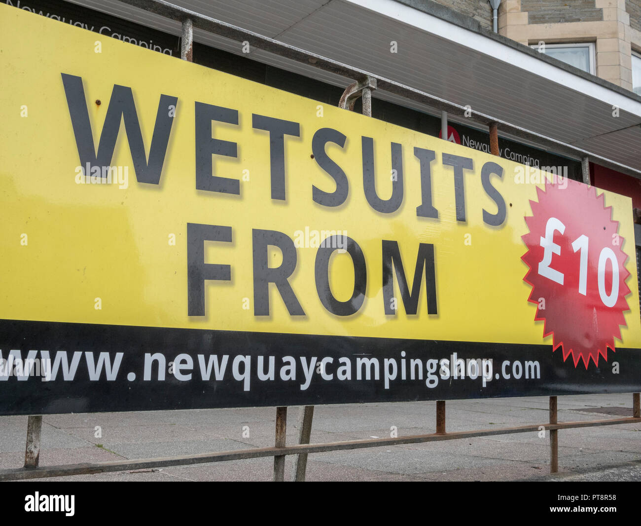 Hoarding outside Newquay camping shop offering surfing wetsuit hire service. Stock Photo