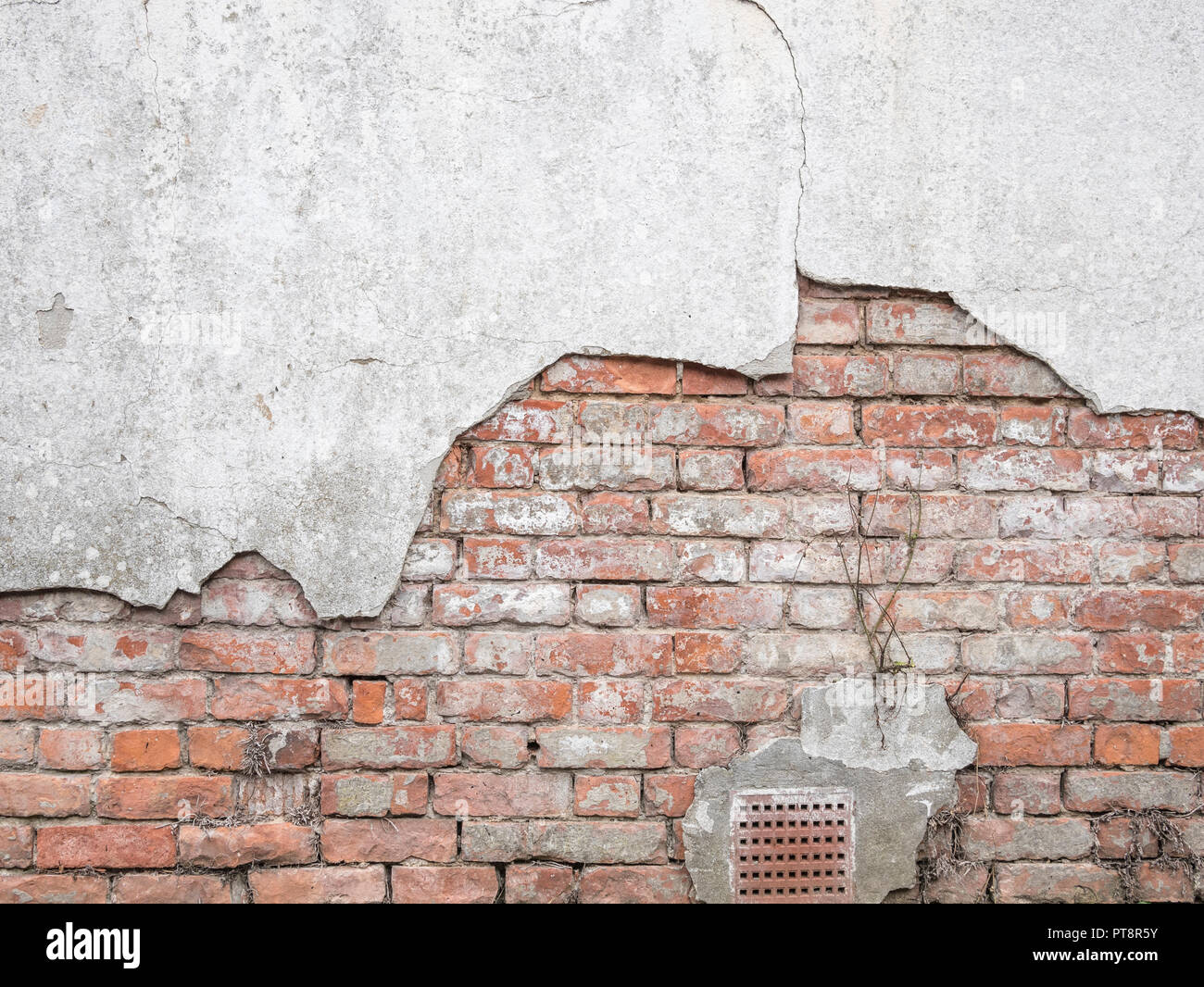 Weathered brick wall in need of repair as cement render falls away. Exposed brickwork, metaphor exposed, hit a brick wall. Old brick wall. Stock Photo