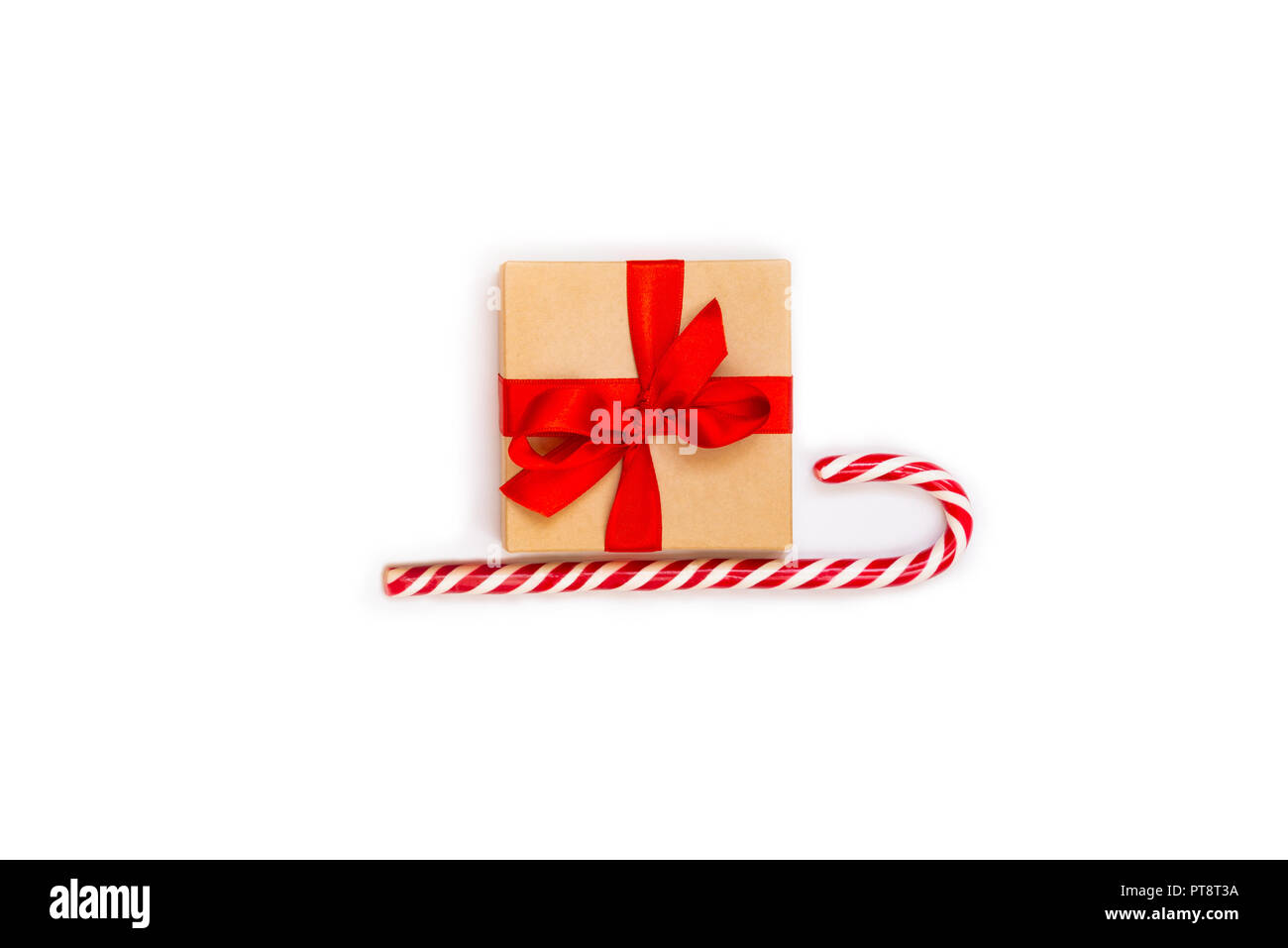 Christmas sledge - a gift box over candy cane on a white background. Abstract christmas concept. Stock Photo