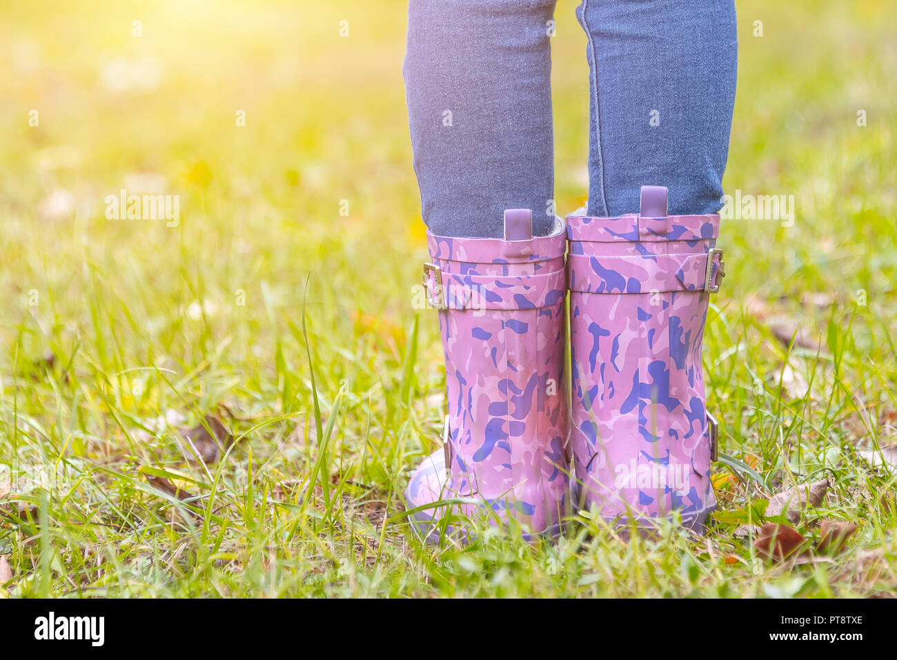 children's feet in rubber boots on yellowed dry grass in autumn Stock ...