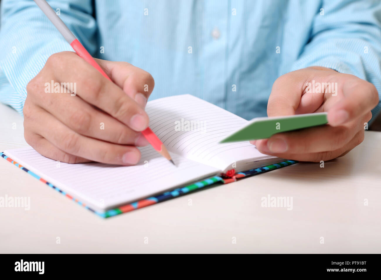 Man is writing address on notebook with looking card. Stock Photo