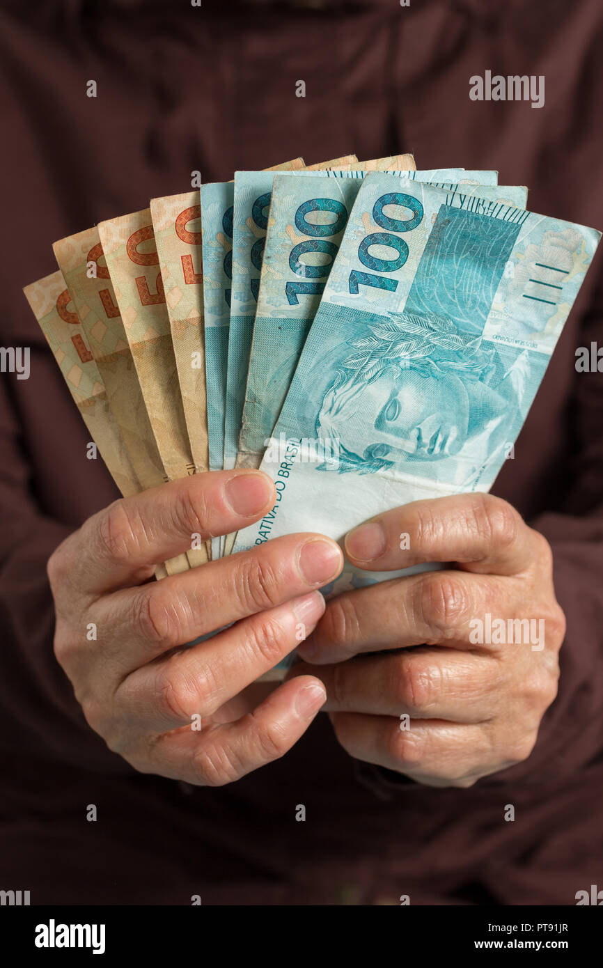 Brazilian currency Real. Money from Brazil. Old retired person paying