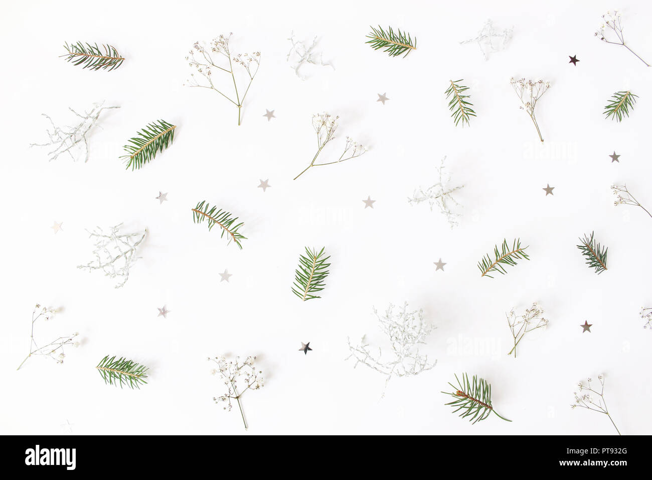 Christmas floral pattern. Winter composition of green spruce tree branches, baby's breath flowers, Calocephalus brownii and silver confetti stars on white table. Festive background. Flat lay, top view. Stock Photo