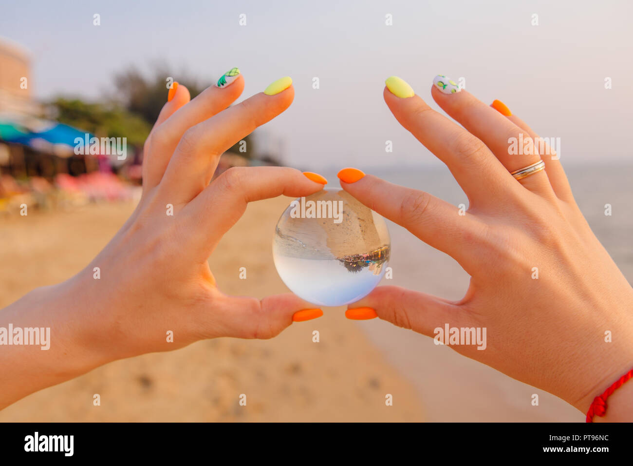 Lens ball in hand with reflection of sea and sunset on the beach Stock ...