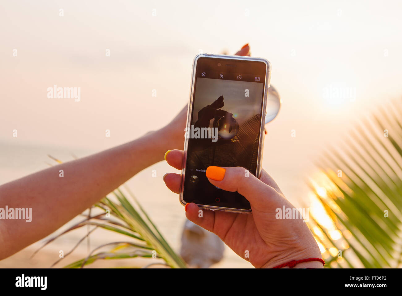 Shooting lens ball with smartphone with reflection of sea and sunset on ...