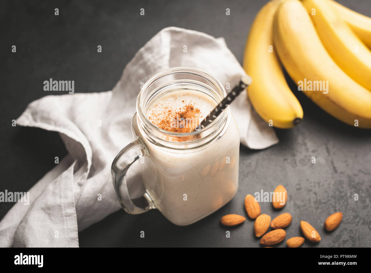 Banana smoothie or protein shake in drinking jar topped with cinnamon. Toned image, selective focus Stock Photo