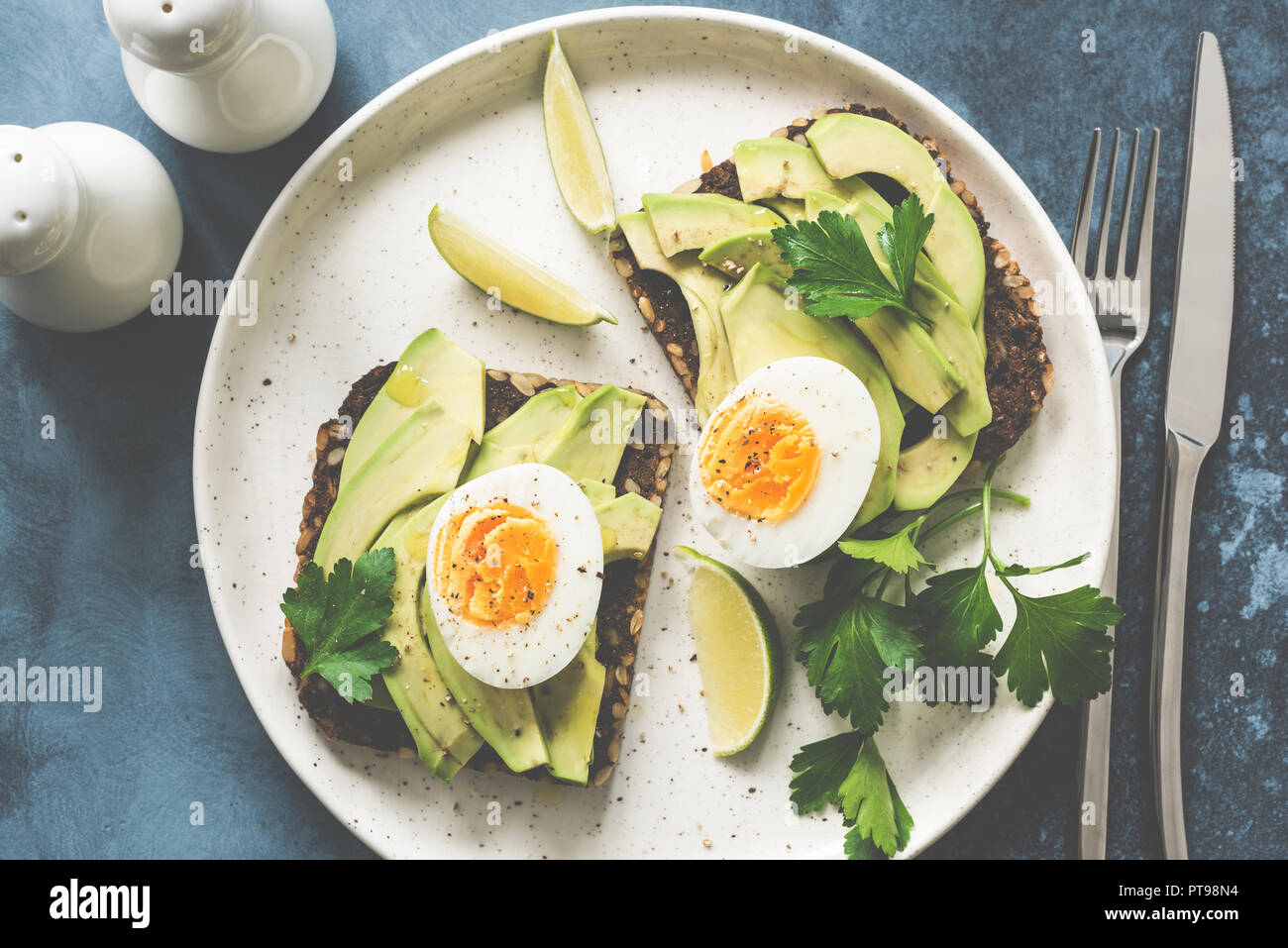 Healthy avocado toasts with boiled egg on a plate. Top view, toned image Stock Photo