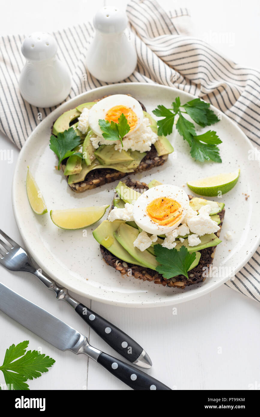 Wholegrain toast with avocado, egg and soft cheese on white plate, healthy breakfast healthy eating concept Stock Photo