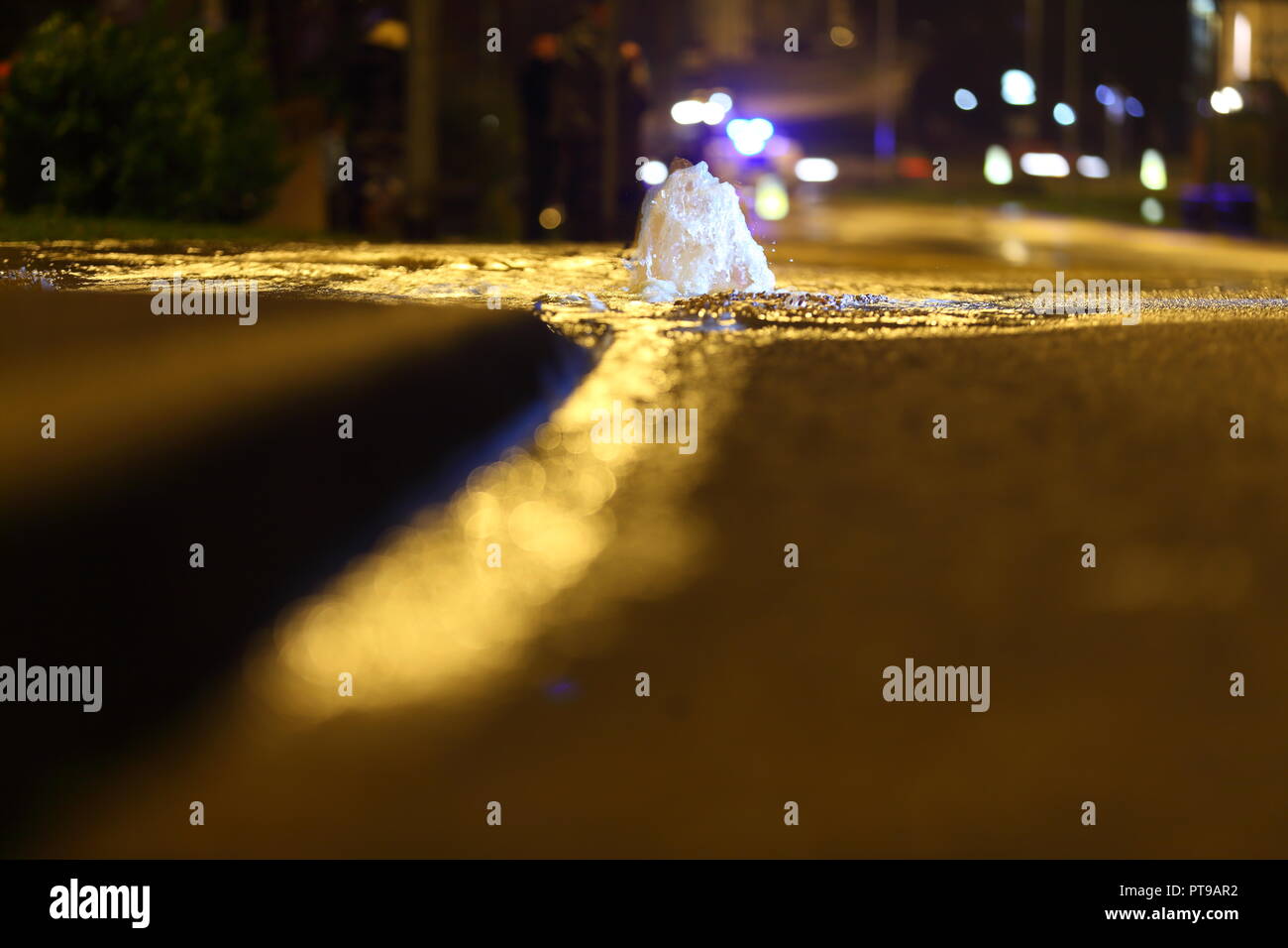 A burst water main erupts from beneath a road surface in Garforth,Leeds