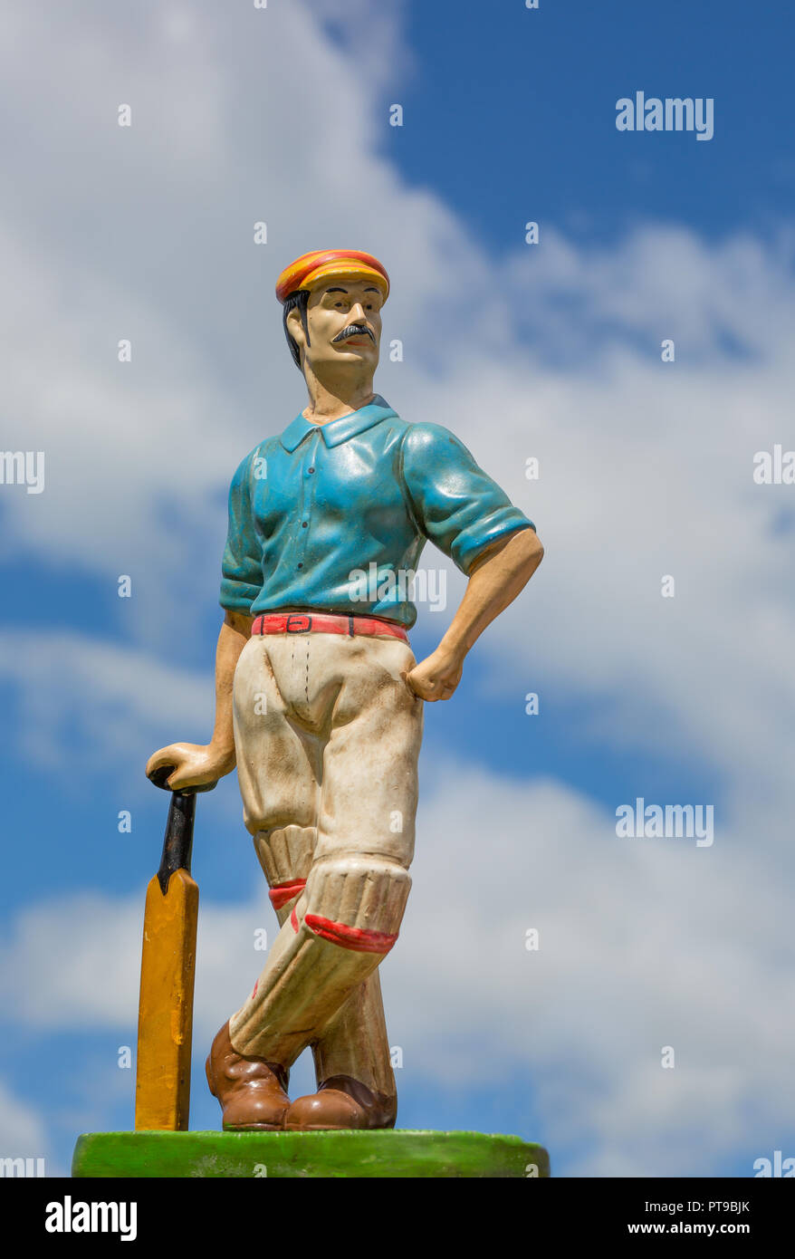Detailed, portrait close up of vintage cricketer ornament against blue sky background. Stock Photo