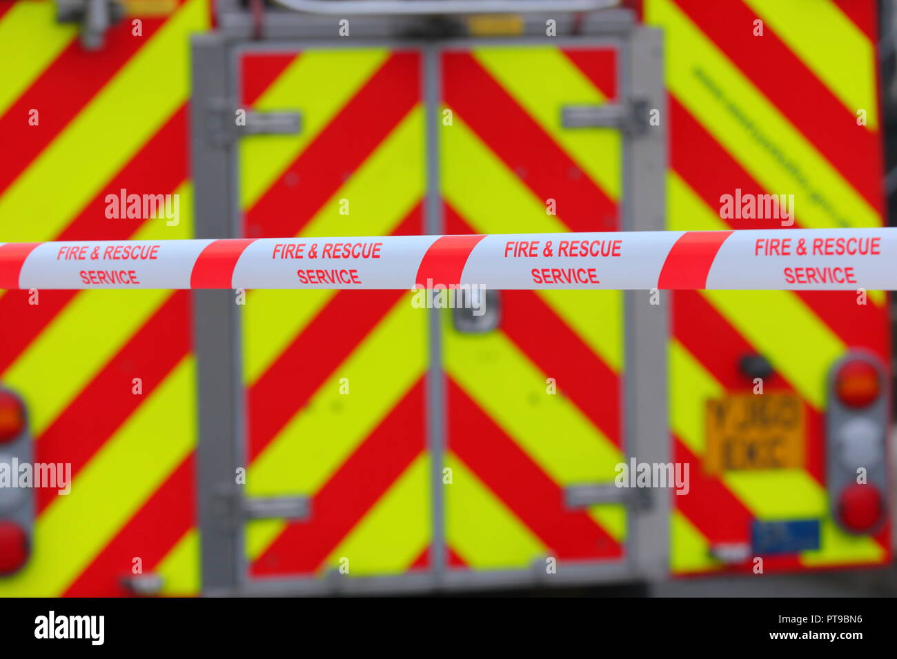 Barrier tape from West Yorkshire Fire & Rescue used to place a cordon across a road . A fire truck is used as the background. Stock Photo