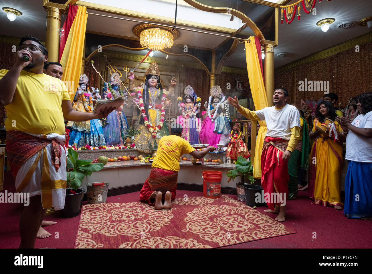 A worshipper making offering to the deities at a Hindu Mandir (temple) in Richmond Hill, Queens, New York. Stock Photo