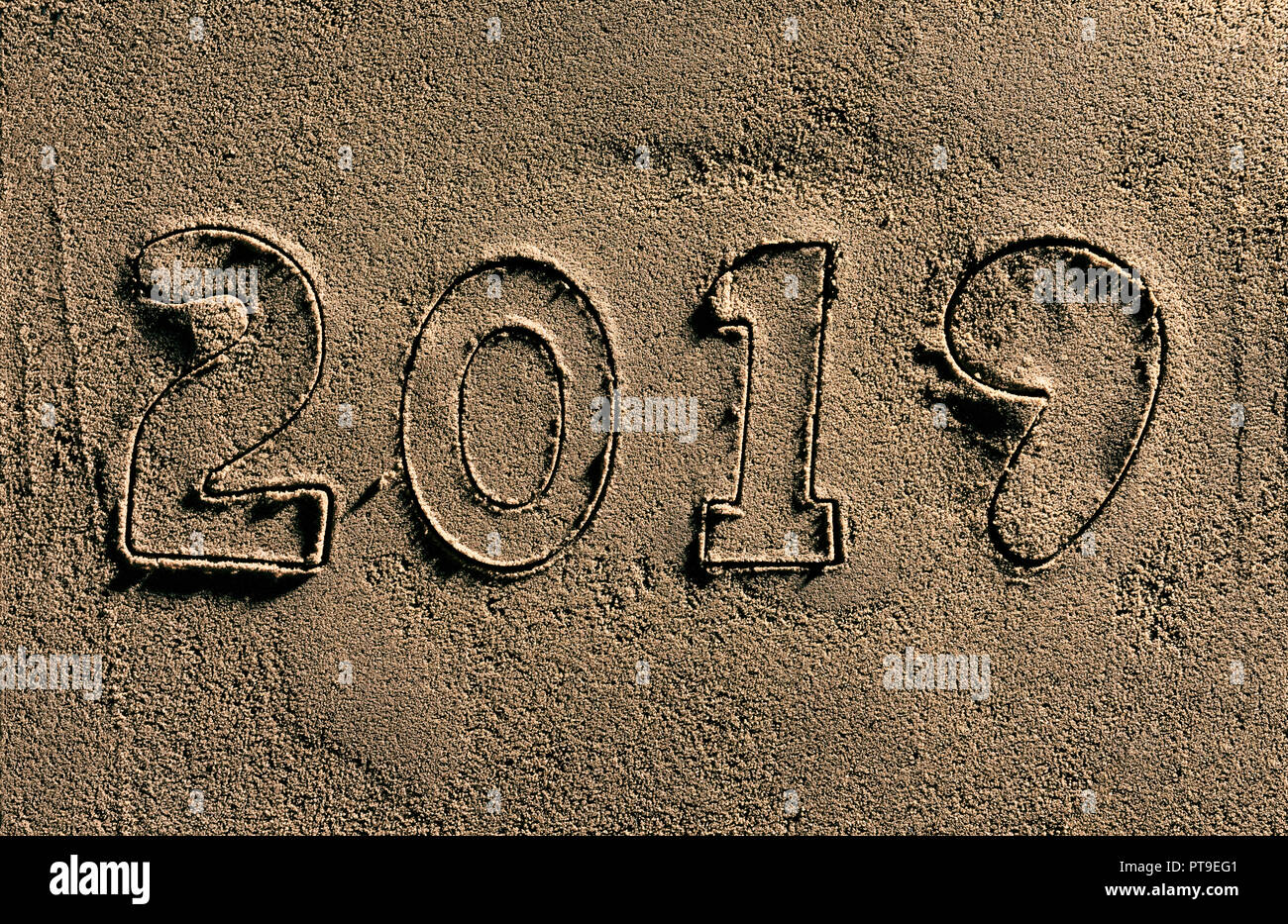 The year 2019 cut into wet sand. Stock Photo