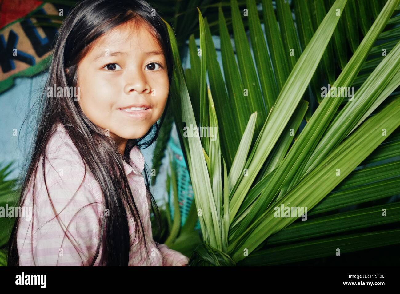 Macedonia, Amazonia / Colombia - MAR 15 2016: young girl preparing for a village event making palm leaf decoration Stock Photo