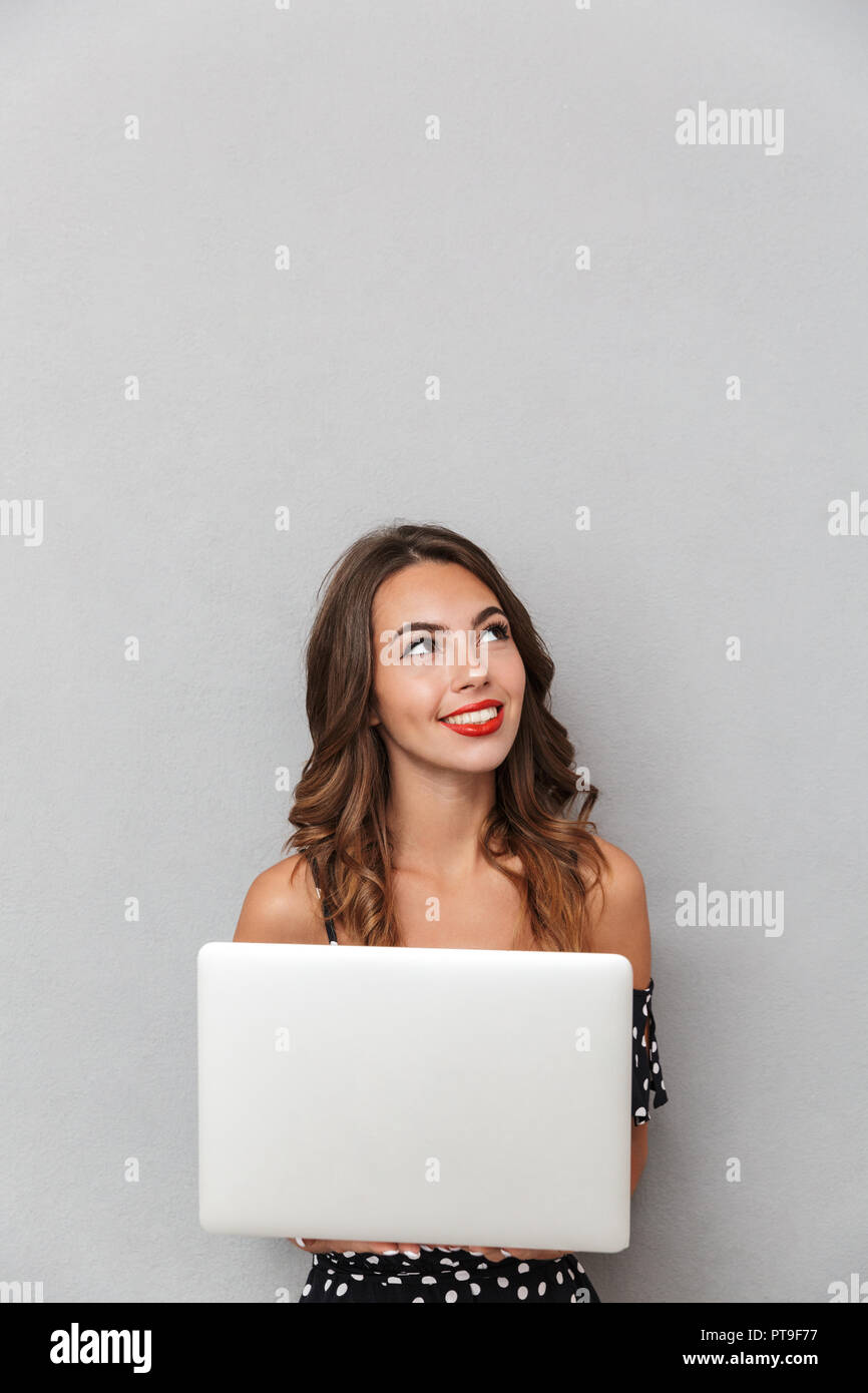 Portrait of a cheerful young girl in dress over gray background ...