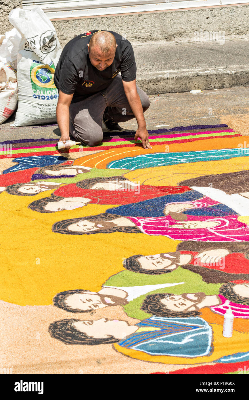 Residents create giant floral carpets made from colored sawdust and decorated with flowers during the 8th Night Celebration marking the end of the Feast of St Michael in the central Mexican town of Uriangato, Guanajuato. Every year the town decorates 5km of road with religious icons in preparation for the statue of the patron saint to be paraded through the town. Uriangato became an international sensation after wowing Brussels with their floral carpet displayed at the Brussels Grand-Place during the Belgium Floral Carpet festival. Stock Photo