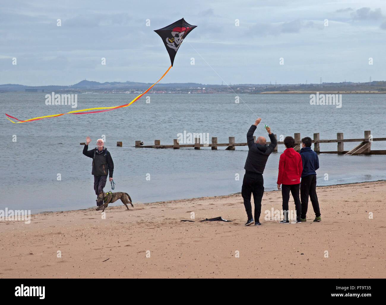Portobello Beach, Edinburgh, Scotland, UK. 8th October 2018. Family flying skull and crossbones kite on a quiet beach. Stock Photo