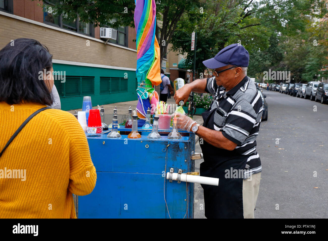 A piraguero making a piragua shaved ice from his pushcart in Manhattan's East Village neighborhood in New York City Stock Photo